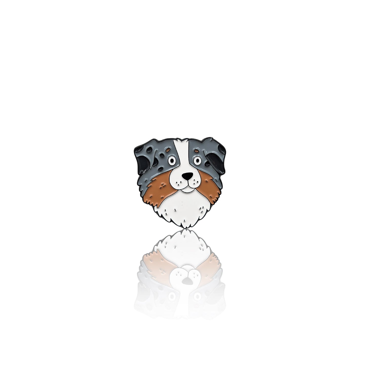 Enamel pin of an Australian Shepherd’s face with a mix of gray, brown, and white fur. The pin has a glossy finish with a reflection on a white background, making it a great accessory for dog lovers.