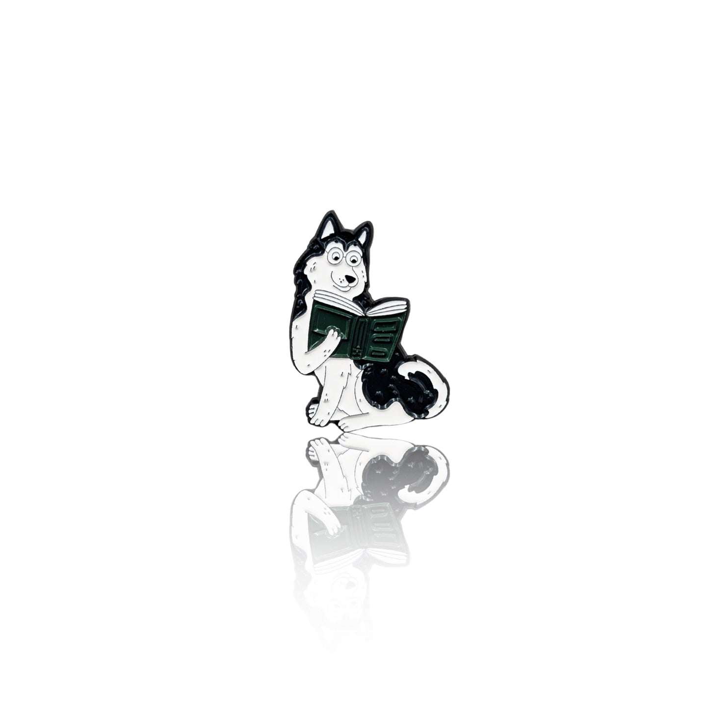Enamel pin of a black-and-white Husky sitting with a book, looking focused and playful. The pin has a glossy finish with a reflection on a white background, making it a great accessory for bookworms and dog lovers.