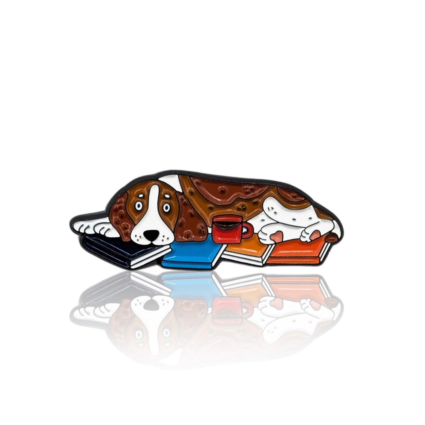 Enamel pin of a cartoon Basset Hound lying on books with a red mug nearby