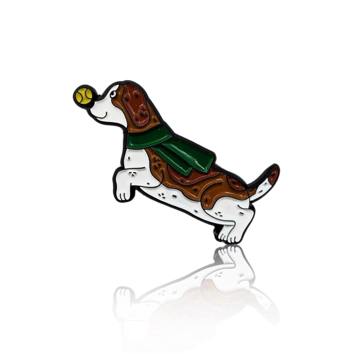 Enamel pin of a cartoon Basset Hound running with a tennis ball in its mouth and wearing a green scarf