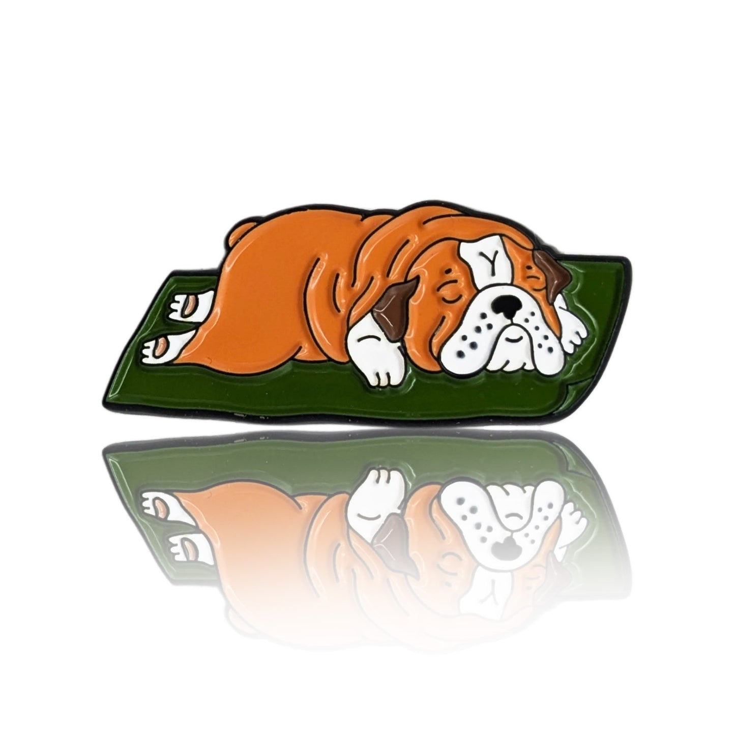 Enamel pin of a cartoon English Bulldog sleeping on a green mat