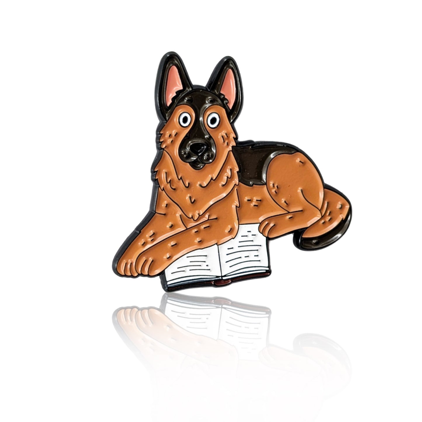 Enamel pin of a cartoon German Shepherd laying on an open book