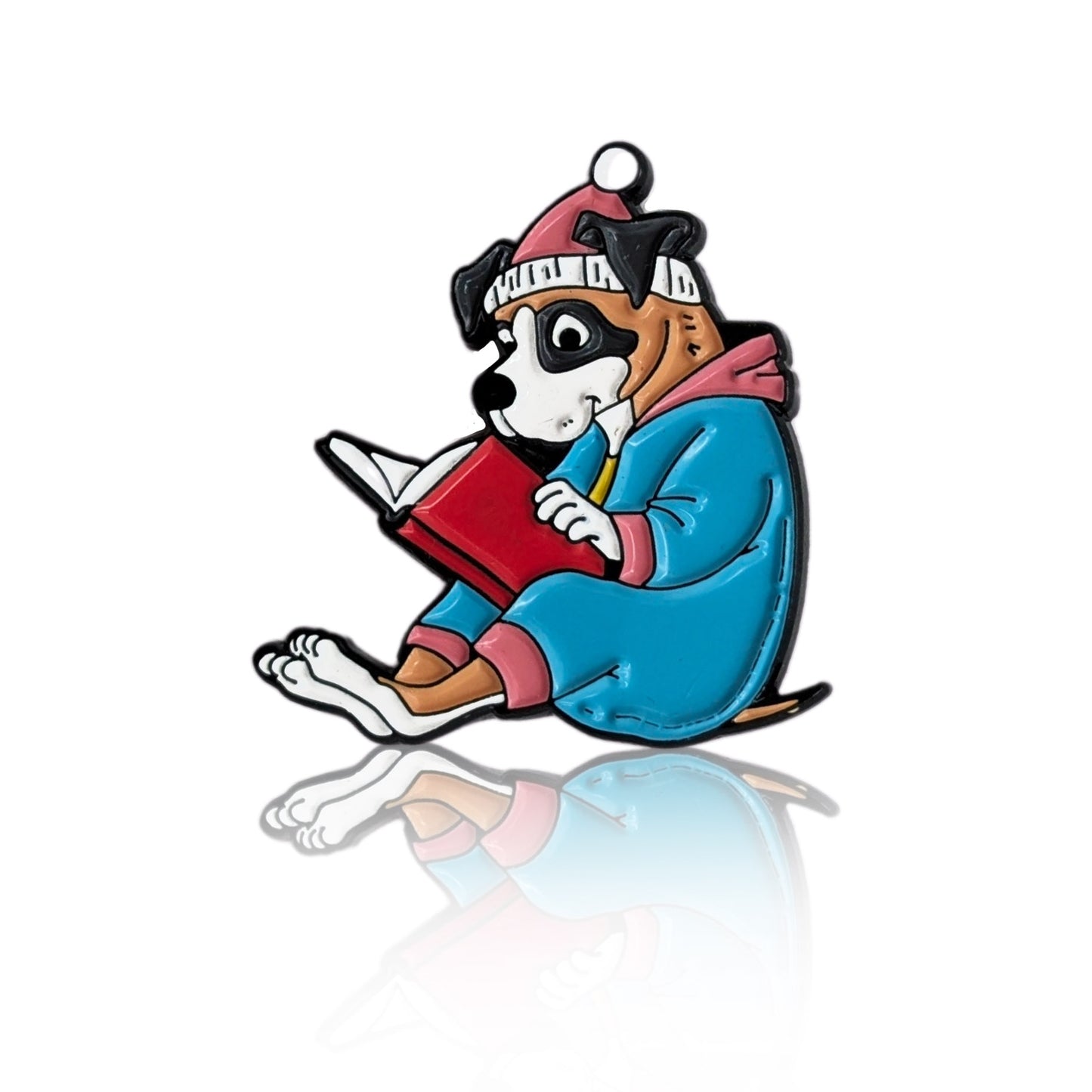 Enamel pin of a cartoon dog in pajamas and a nightcap reading a book