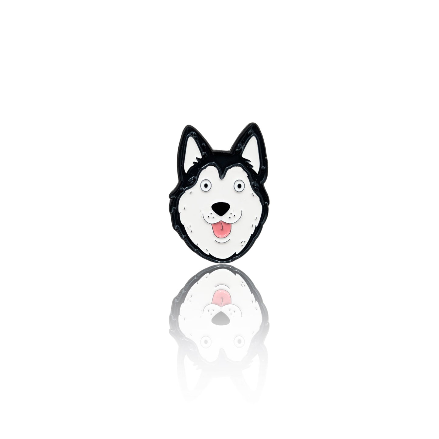 Enamel pin featuring a cartoon-style Husky face with black-and-white fur, bright eyes, and a tongue-out expression. The pin has a glossy finish with a reflection on a white background, making it a fun accessory for dog lovers.