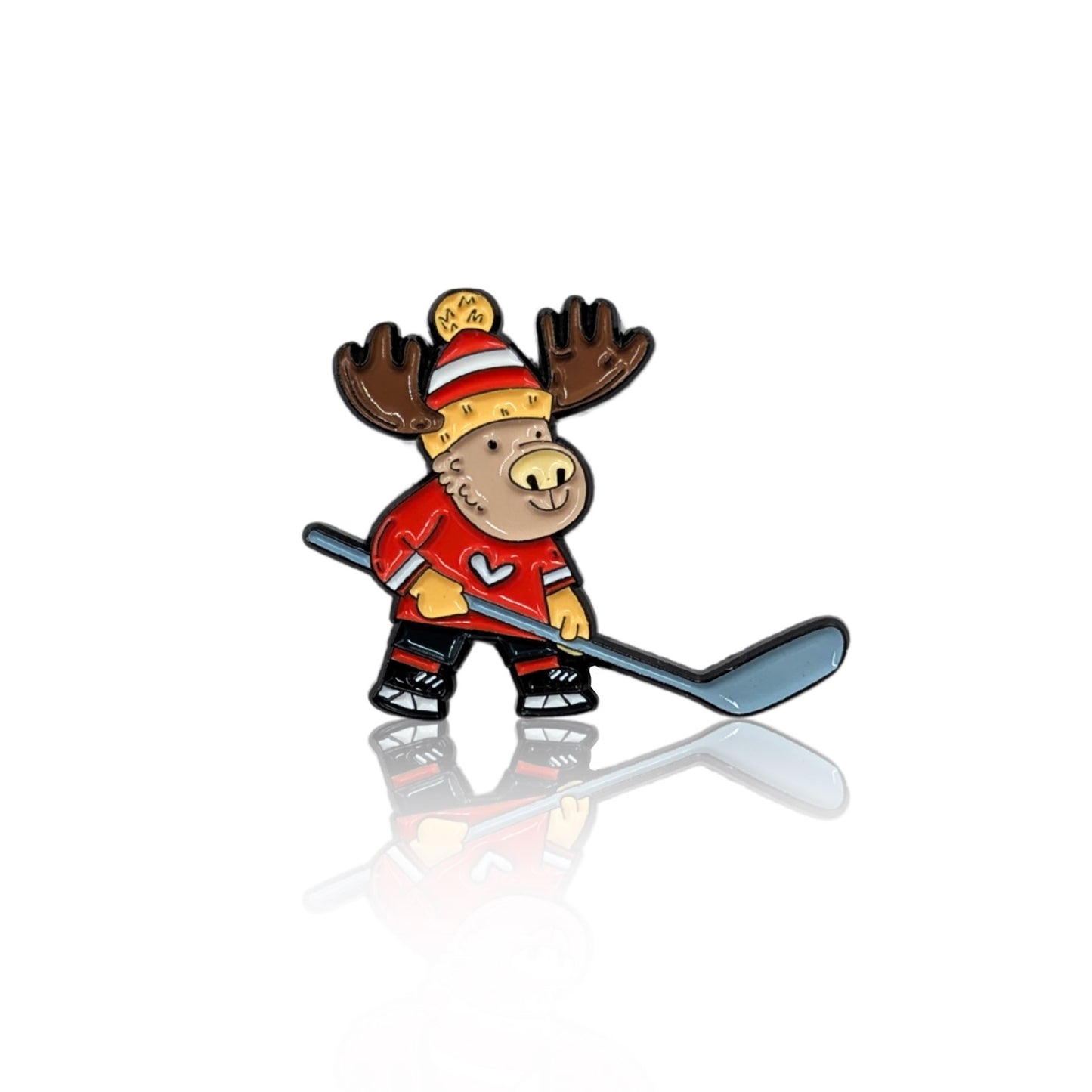 Enamel pin featuring a cartoon moose playing hockey, dressed in a red jersey with a heart emblem and a cozy winter hat. The moose holds a hockey stick, ready for action, making it a perfect accessory for hockey lovers and Canadian pride enthusiasts. The pin has a glossy finish with a reflection on a white background.