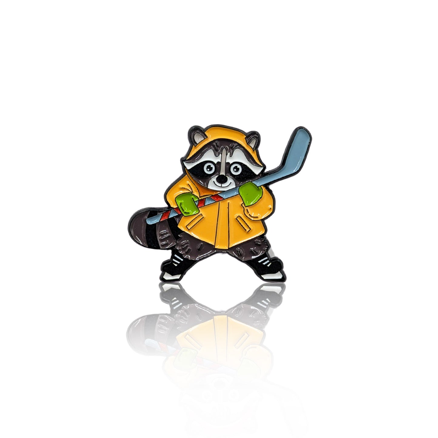 Enamel pin featuring a raccoon in a yellow raincoat, green gloves, and black sneakers, holding a hockey stick in a playful stance. The pin has a glossy finish with a reflection on a white background, making it a great accessory for hockey lovers and Canadian wildlife fans.