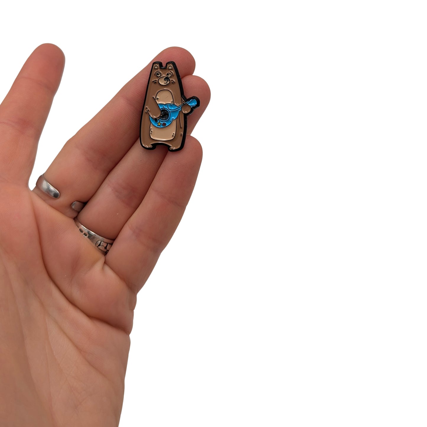Bear the Bard enamel pin held in hand, featuring a cute bear playing a blue guitar