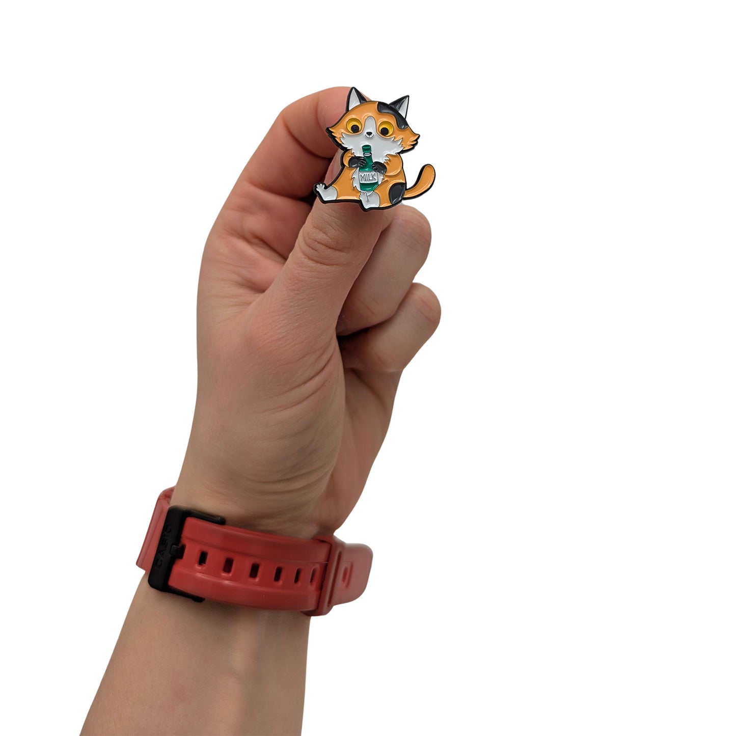 Cat enamel pin held in hand, showing an orange and black cat sitting and holding a green milk bottle
