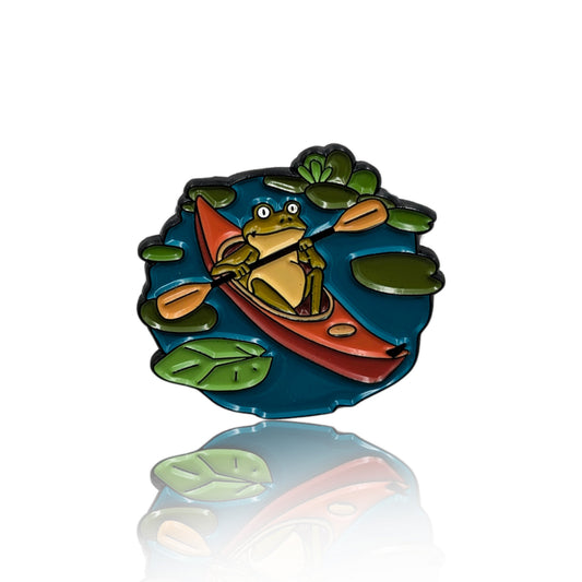 Enamel pin of a frog in a red canoe paddling through lily pads on blue water