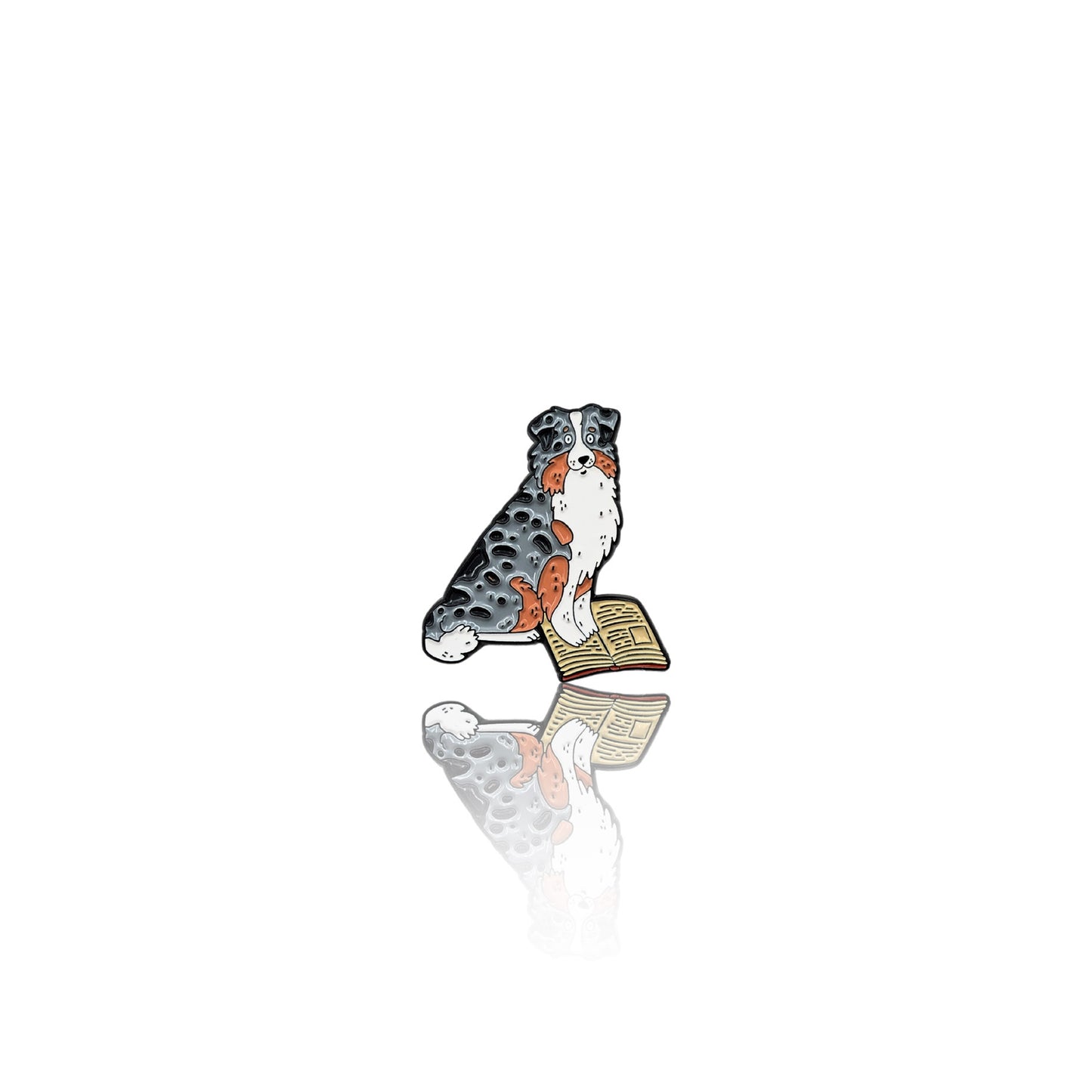  Enamel pin featuring an Australian Shepherd sitting with an open book, gazing thoughtfully. The pin has a glossy finish with a reflection on a white background, making it a perfect accessory for book and dog lovers.