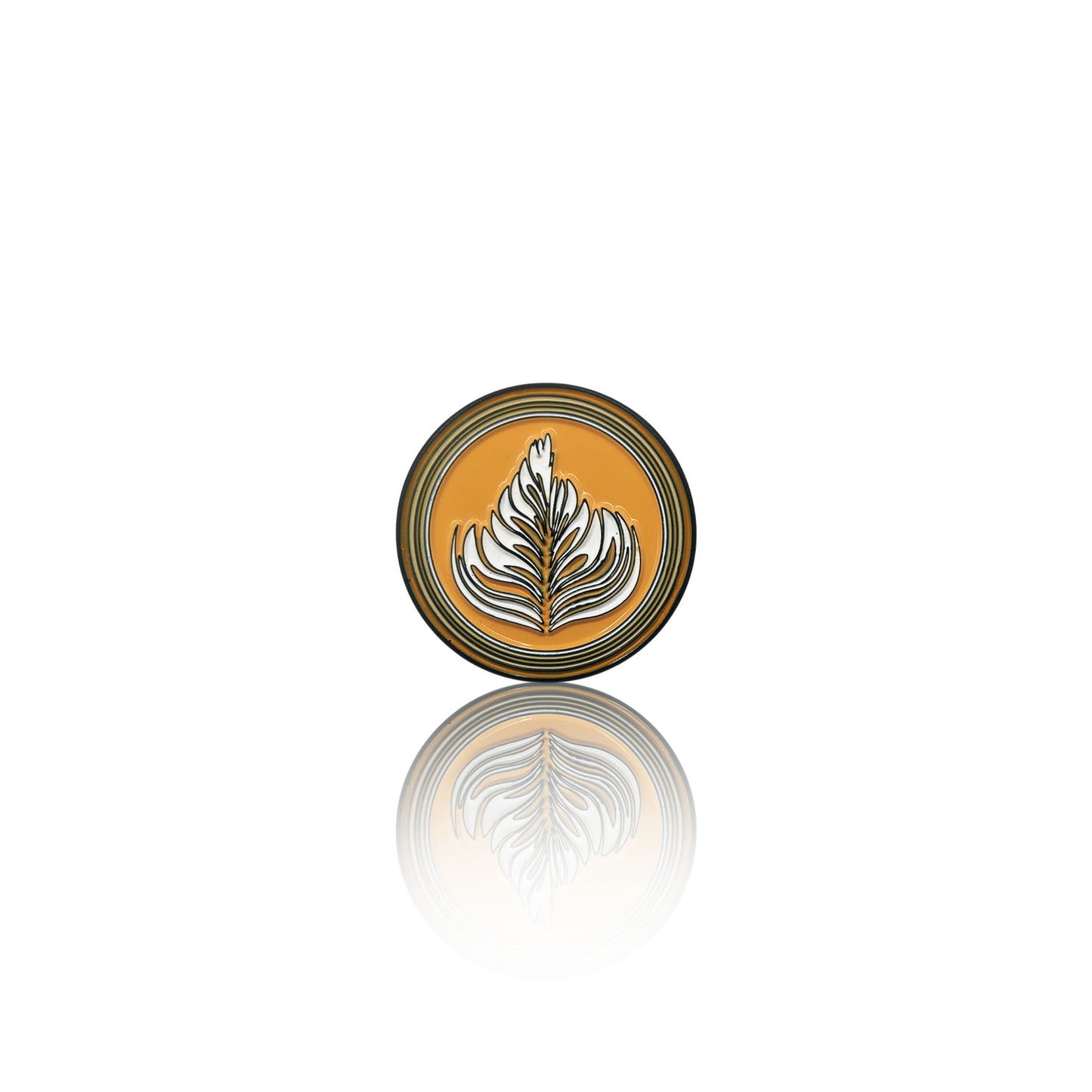 Round enamel pin with a golden-brown coffee base and detailed white latte art design, resembling a perfect barista pour.