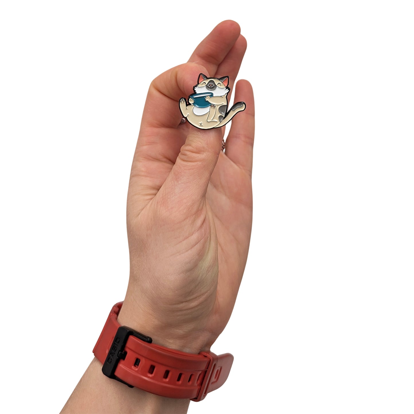Cozy cat enamel pin holding a mug, shown in hand, featuring a relaxed smiling cat design
