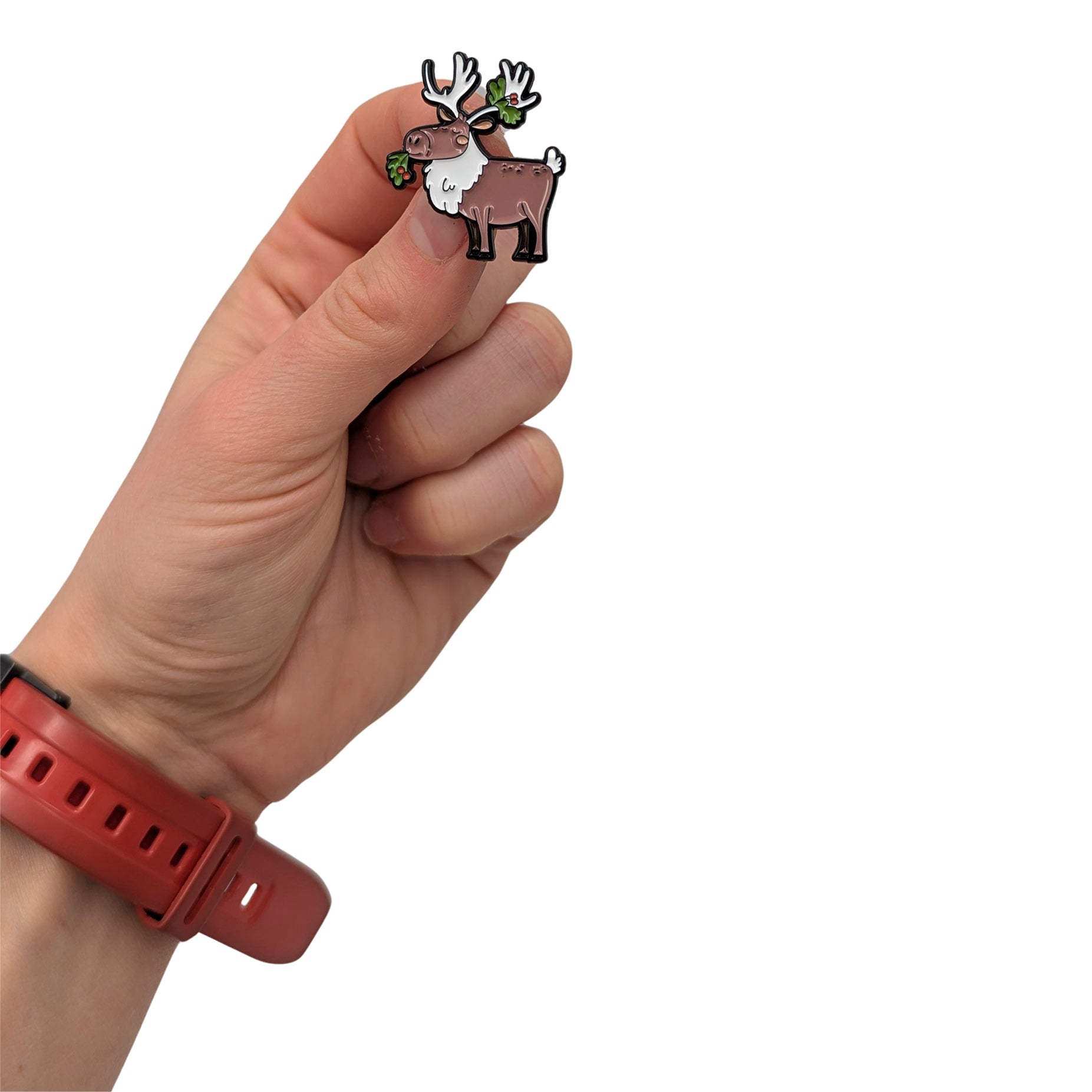Festive caribou enamel pin held in hand, featuring a cute caribou with antlers and greenery details