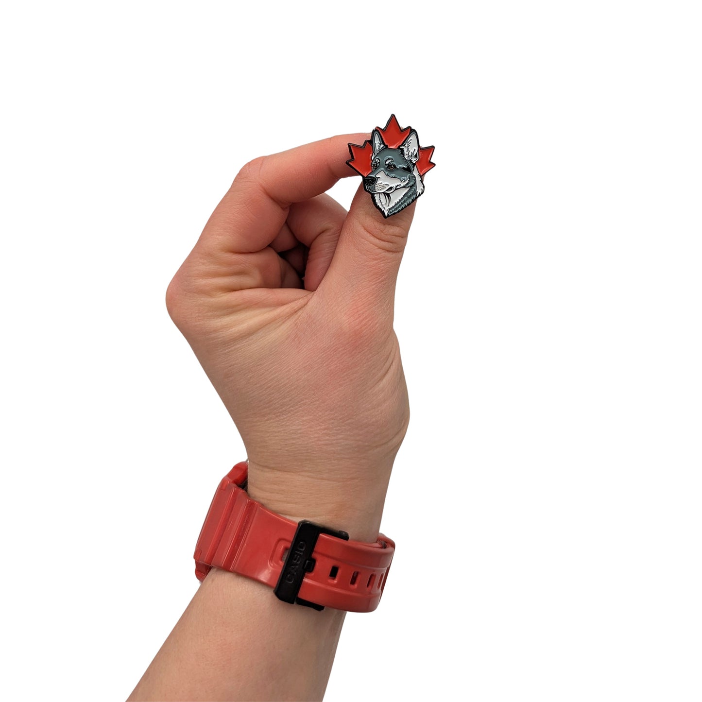 hand holding grey and white husky enamel pin with red maple leaf background
