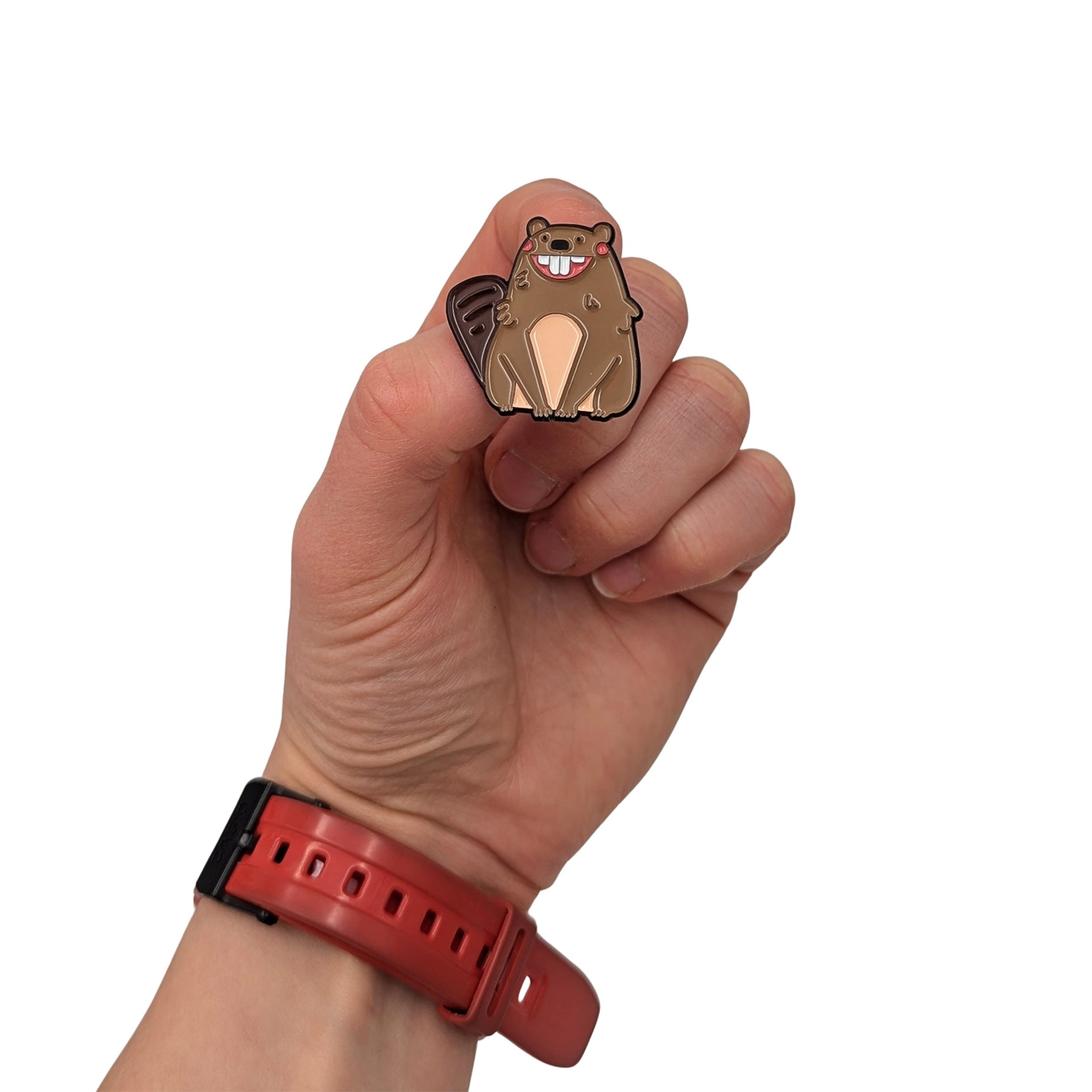 Smiling beaver enamel pin held in hand, featuring a cute cartoon beaver with buck teeth in warm brown tones
