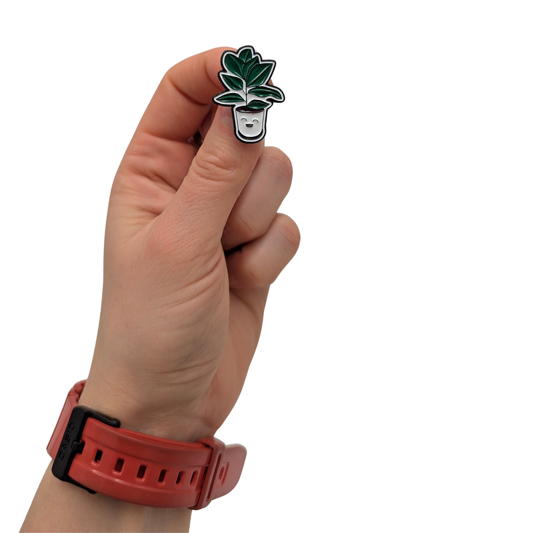 Smiling potted plant enamel pin held in hand, featuring green leafy houseplant in a white planter