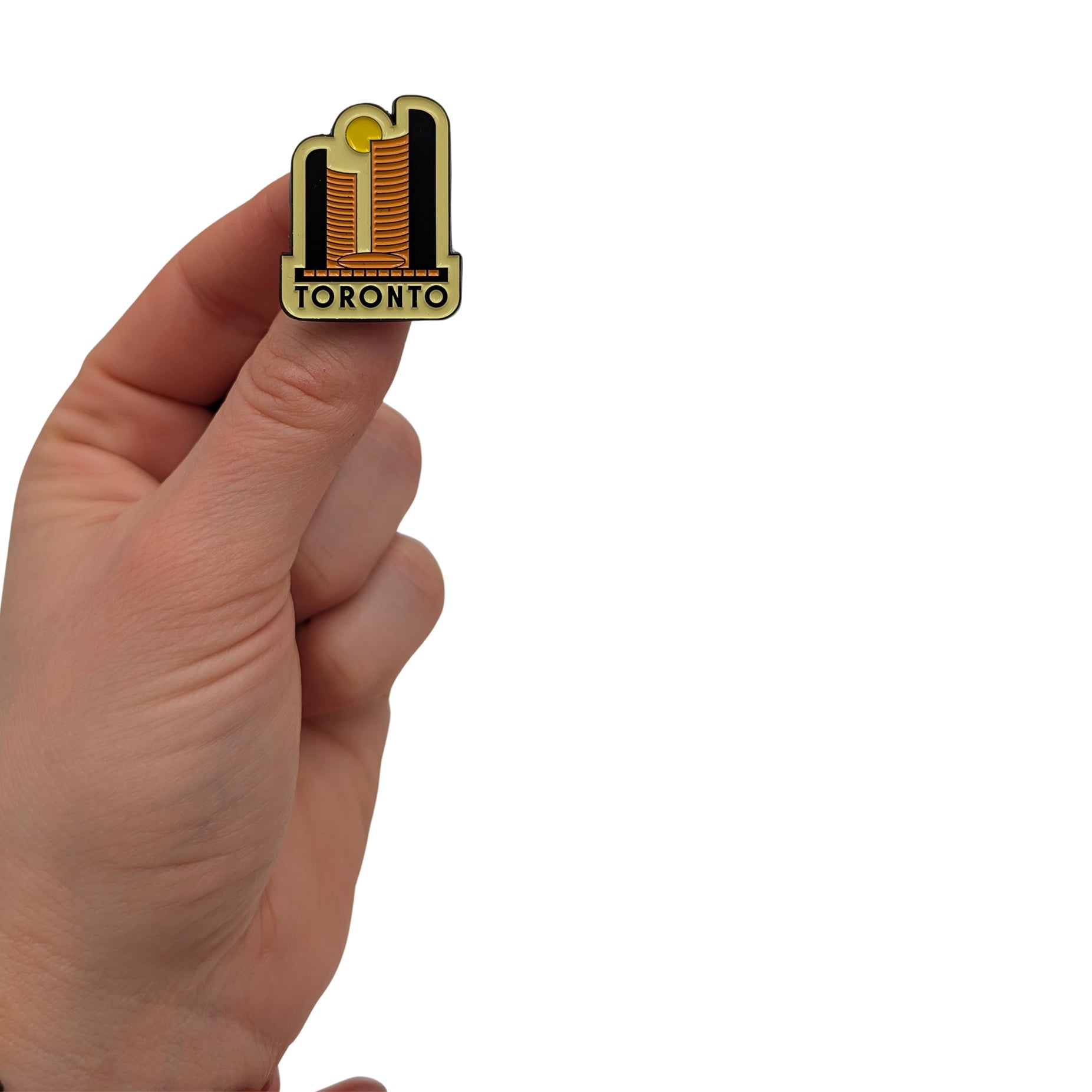 Toronto skyline enamel pin held in hand, showing stylized golden towers with black and gold detailing